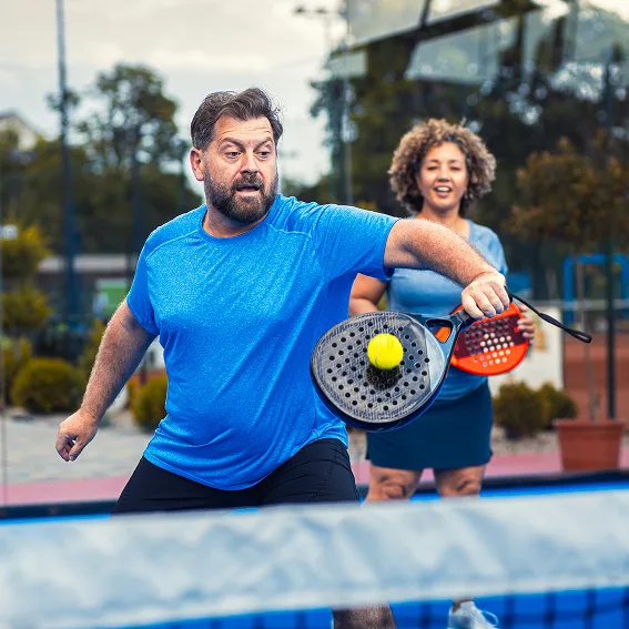 mixed adult couple palying padel on outdoor court